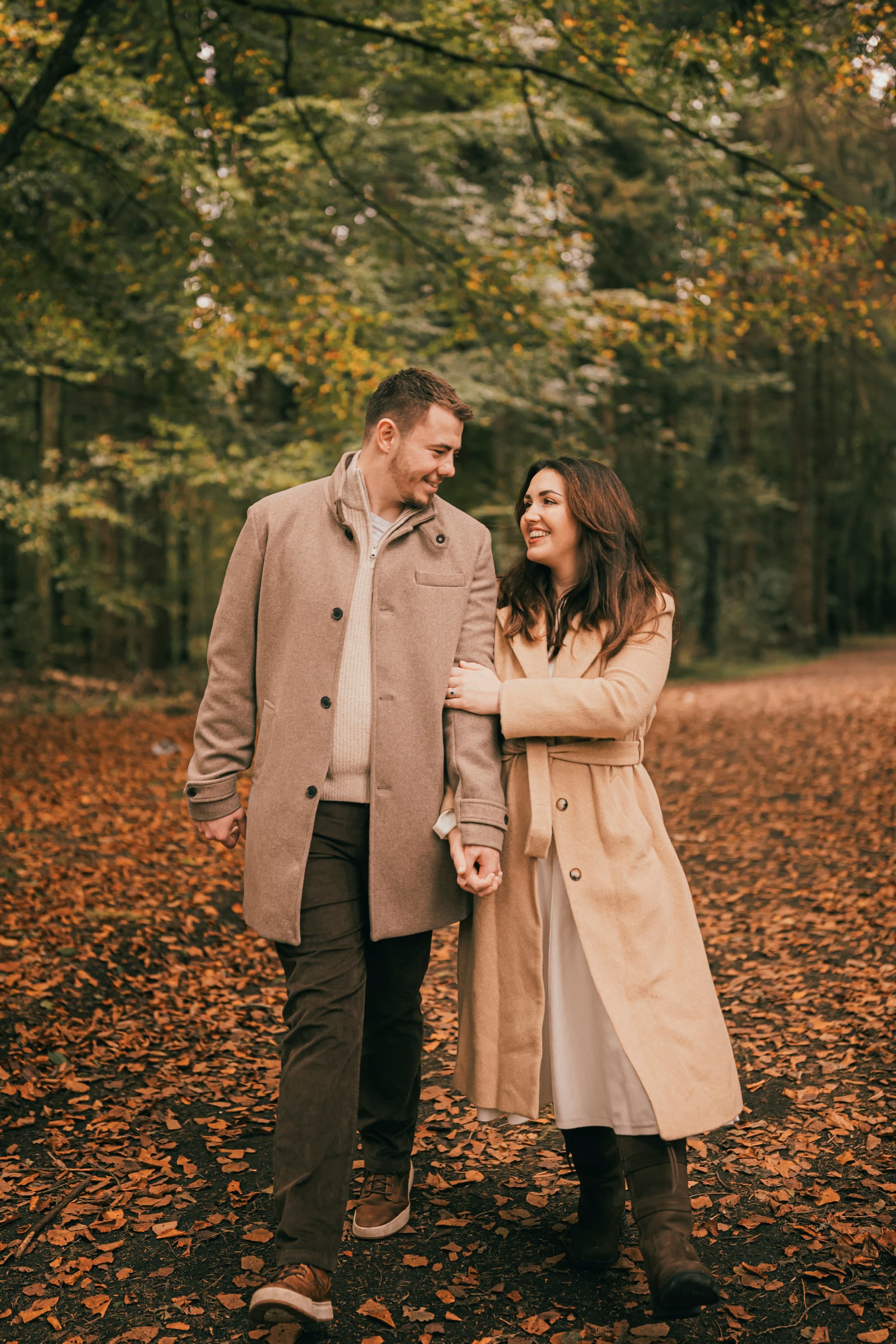 Conor and Erin laughing together on a woodland path in autumn